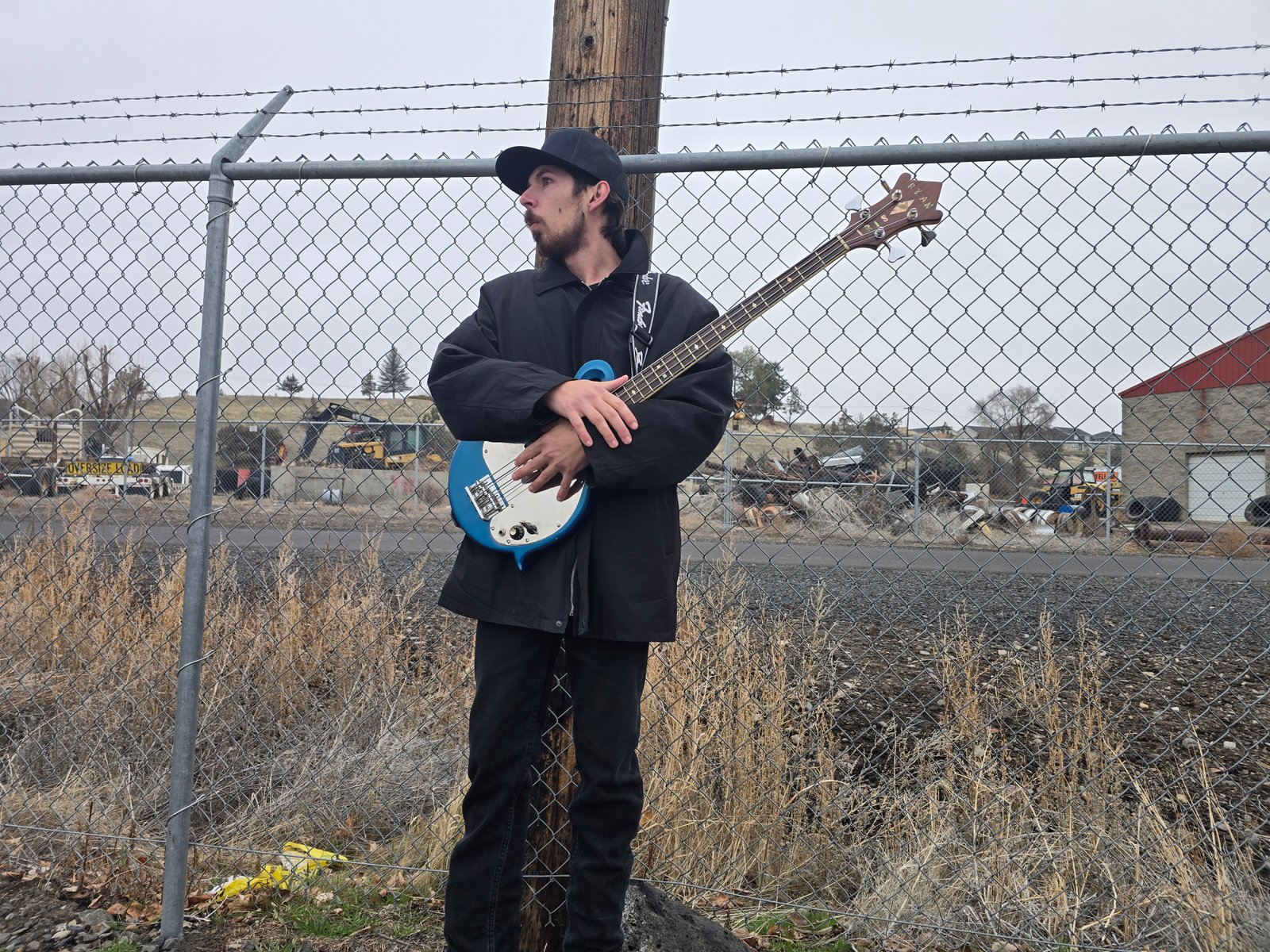 Band member with blue bass against fence