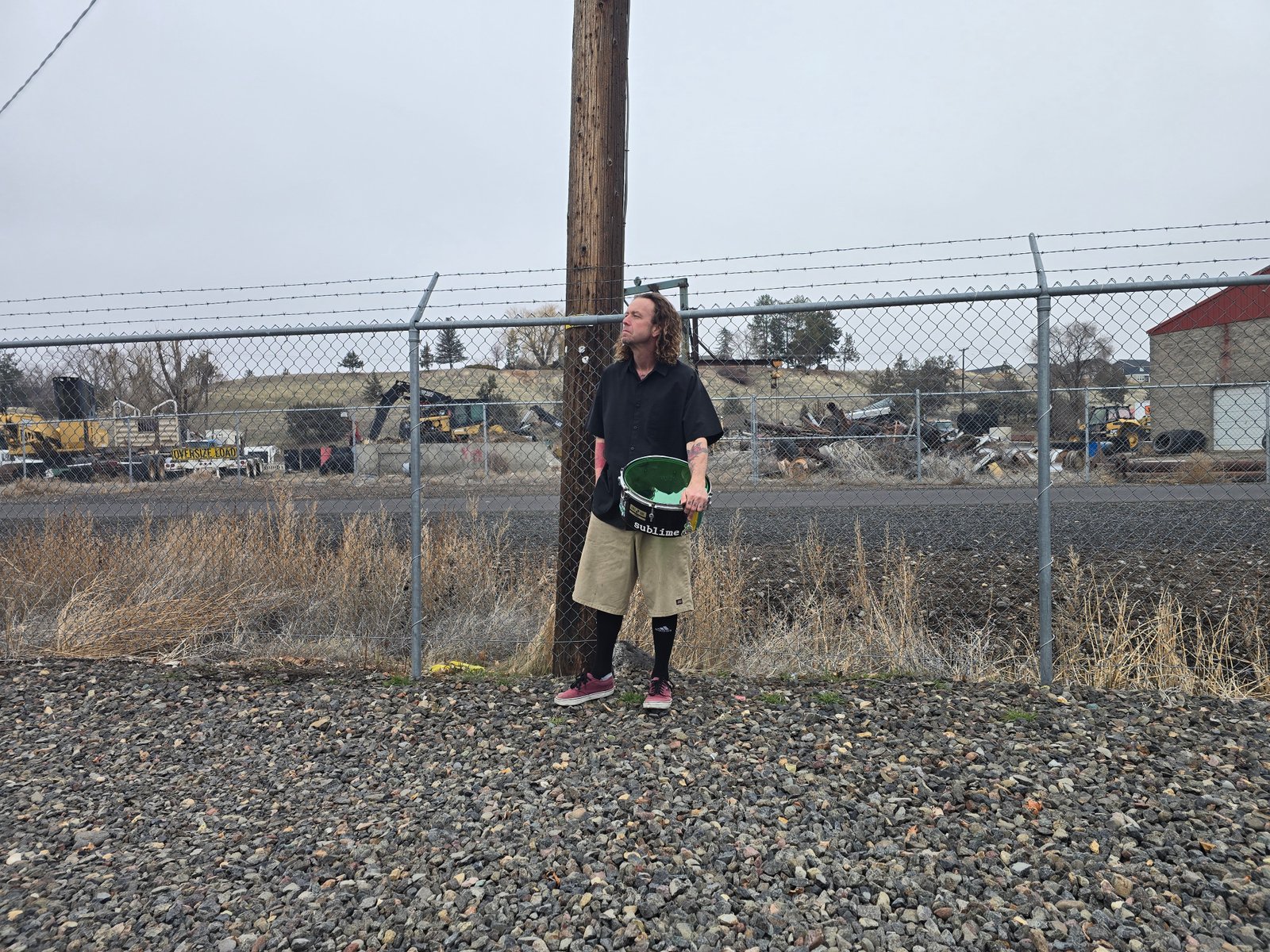 Long-haired band member against fence